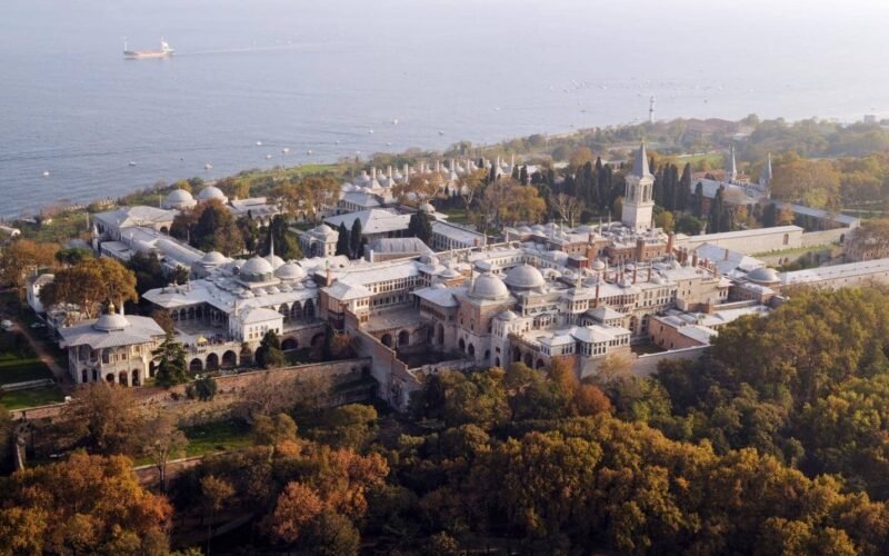 An aerial view of Topkapi Palace in Istanbul, with its historic buildings and courtyards surrounded by greenery and overlooking the sea.